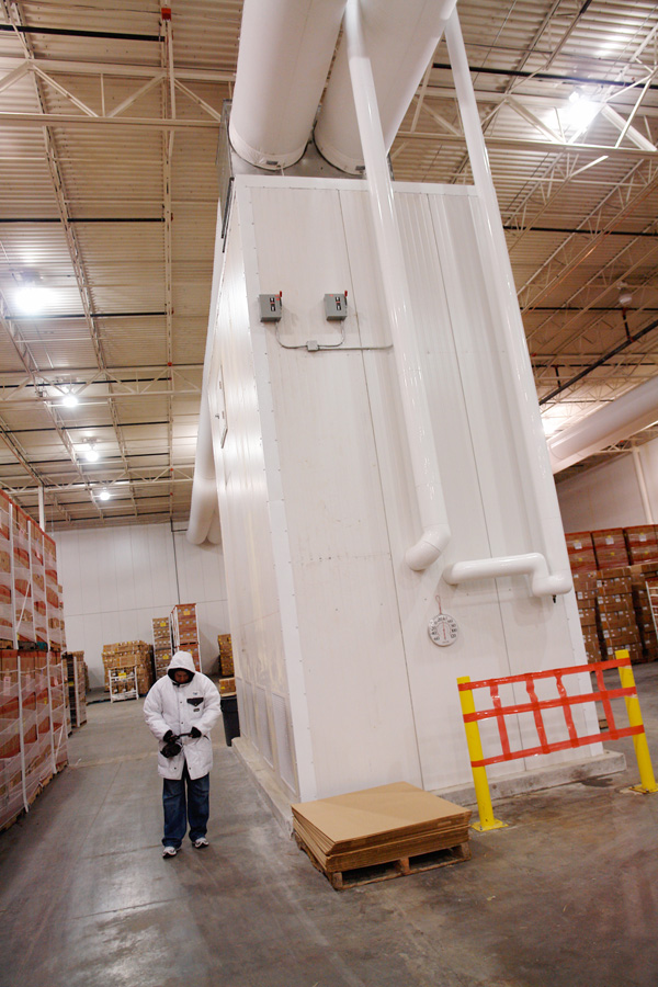 A pre-cooling air handler standing full height inside the cooler, ducts feeding it from the ceiling
