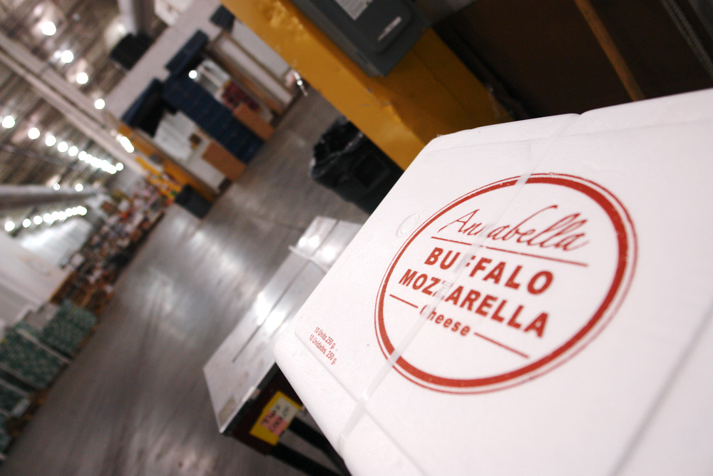 A carton of Anabella buffalo mozzarella on a pallet, the warehouse floor stretching away behind it