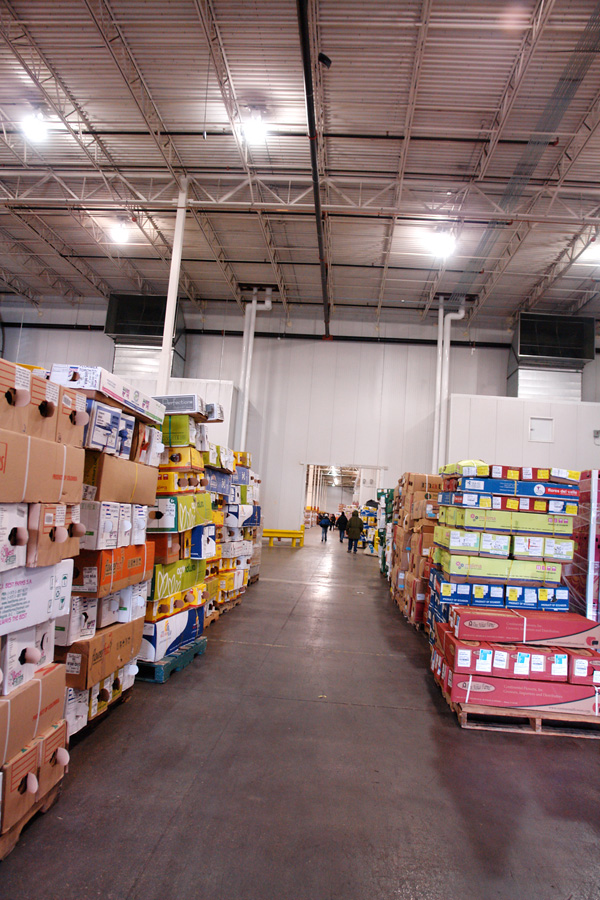 An aisle between pallets of flower boxes stacked above head height