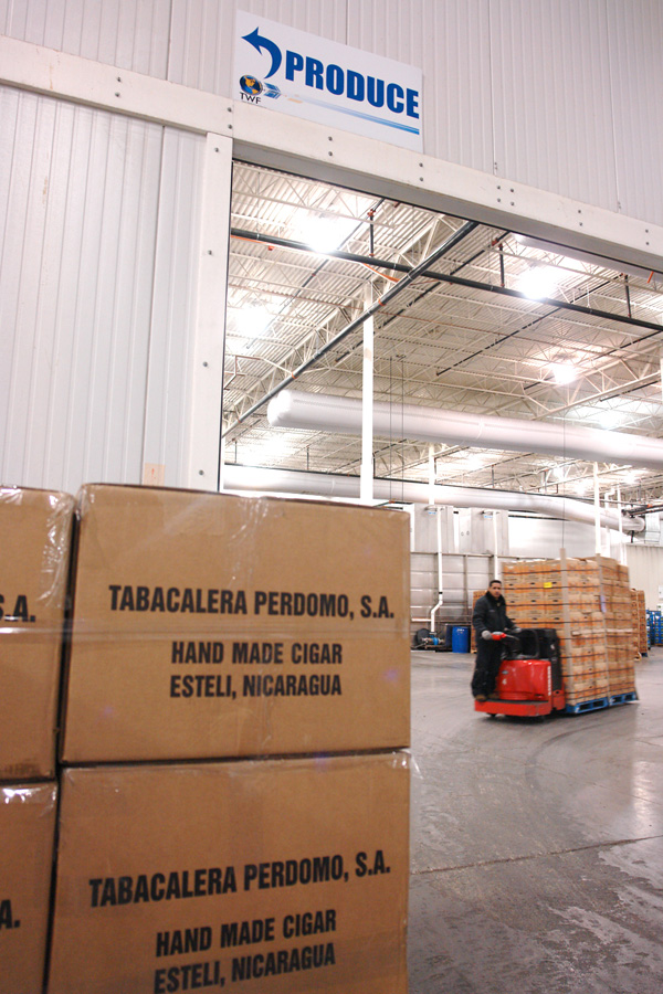 Cartons of hand-made cigars from Estelí, Nicaragua stacked beneath a bay sign reading Produce